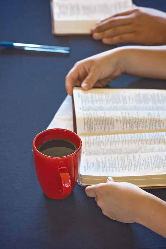 open bible and mug of coffee on table